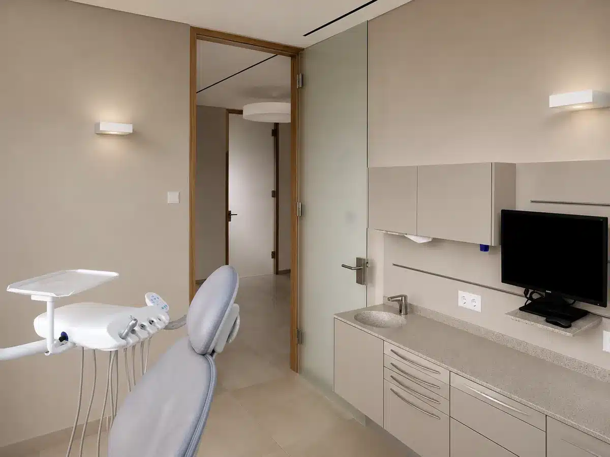 Modernes Zahnarzt-Behandlungszimmer mit erneuerter Waschtisch-Zeile, Wandflächen und Holztür.