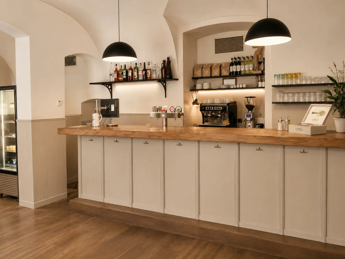 Café-Theke mit erneuerten Fronten in Creme und massiver Holz-Arbeitsplatte im Gewölberaum.
