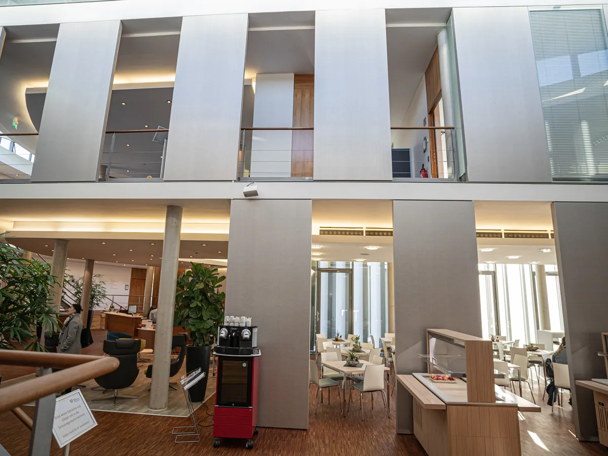 Weitläufiges Büro-Foyer mit Empore, Sitzbereich und wandhohen Akustik-Flächen.