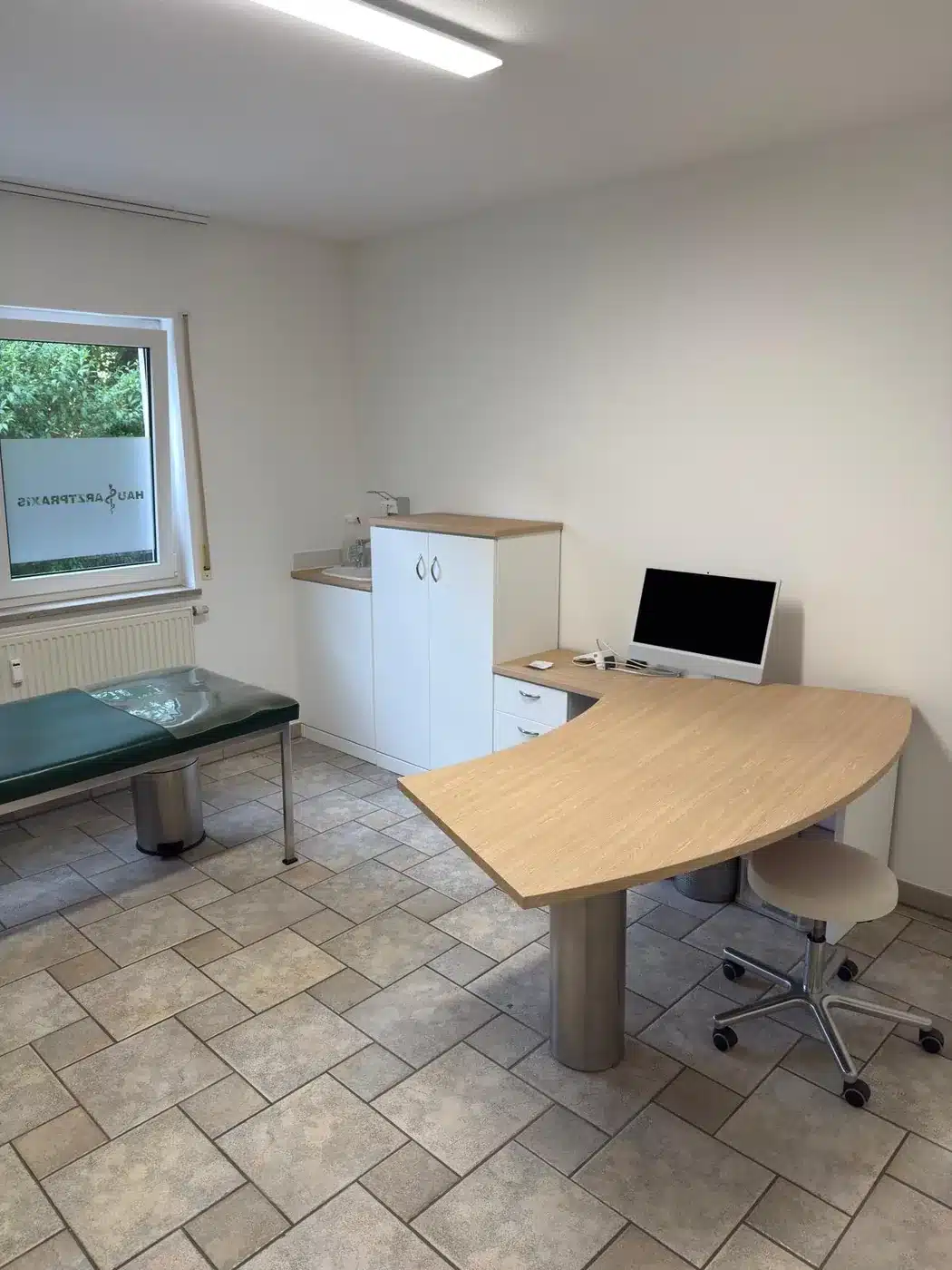 Dasselbe Behandlungszimmer nach der Erneuerung: Schreibtisch- und Schrankoberflächen in heller Eiche, im laufenden Betrieb erneuert.
