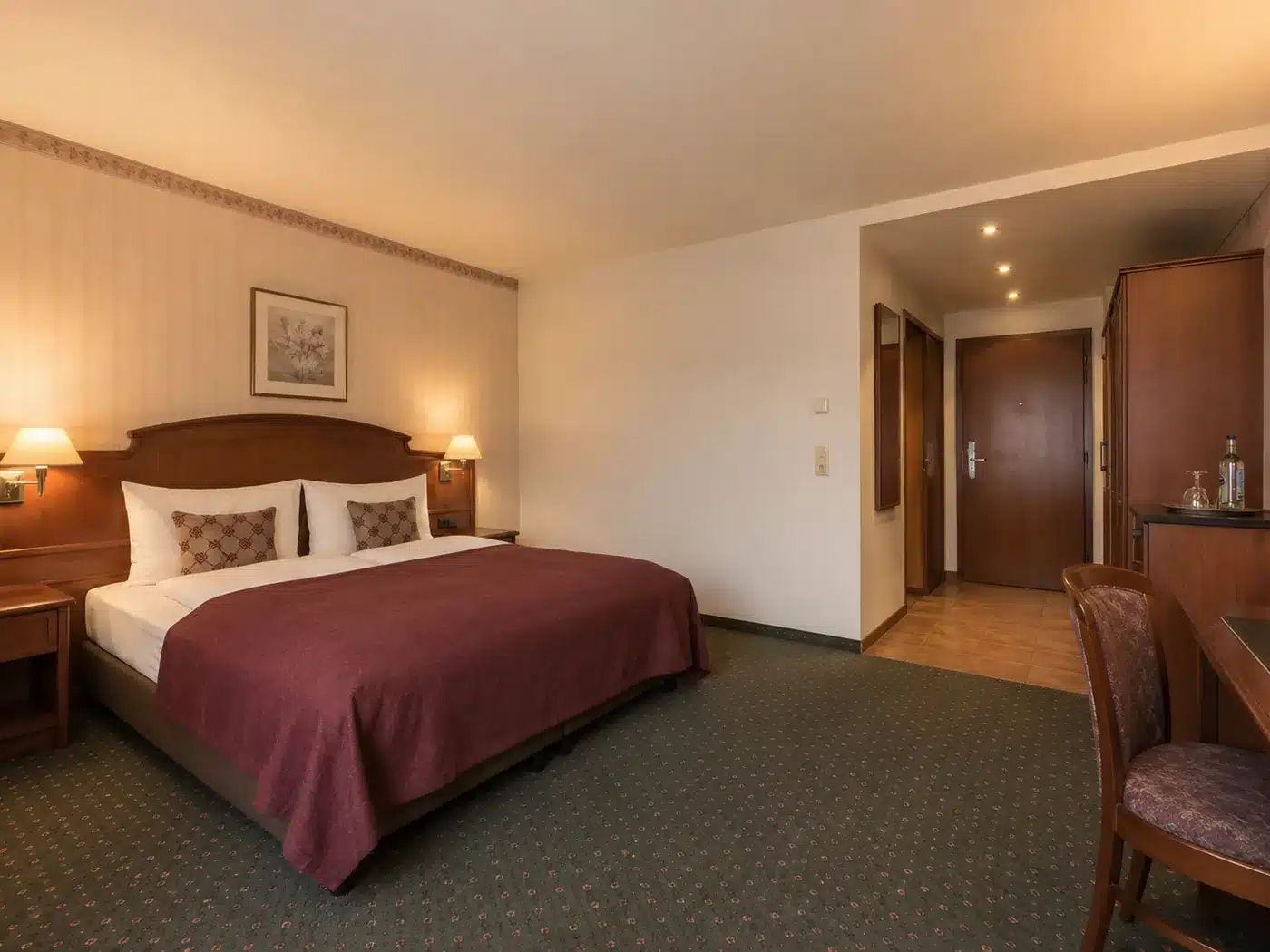 Hotelzimmer mit dunkler Möblierung und Teppichboden vor der Renovierung