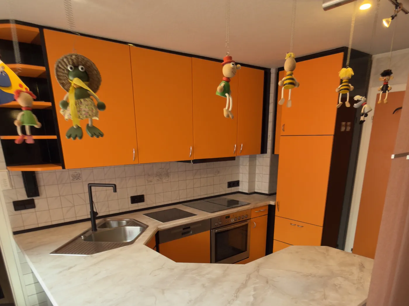 Dieselbe Küche nach der Folierung mit orangen Fronten und heller Marmor-Theke