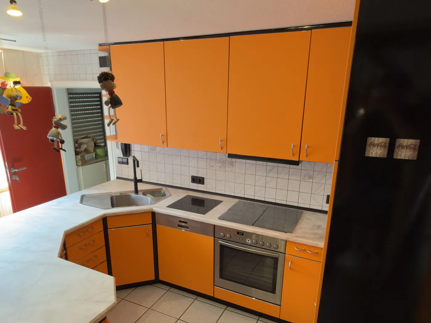 Dieselbe Küchenzeile nach der Folierung mit orangen Fronten und heller Arbeitsplatte